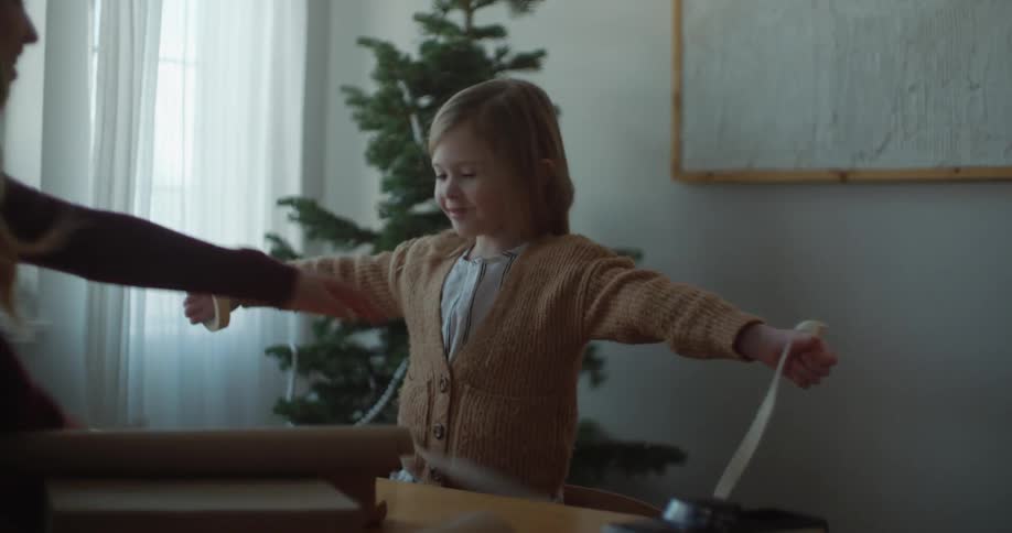 Mother cuts the tape while her daughter holds it to wrap gifts
