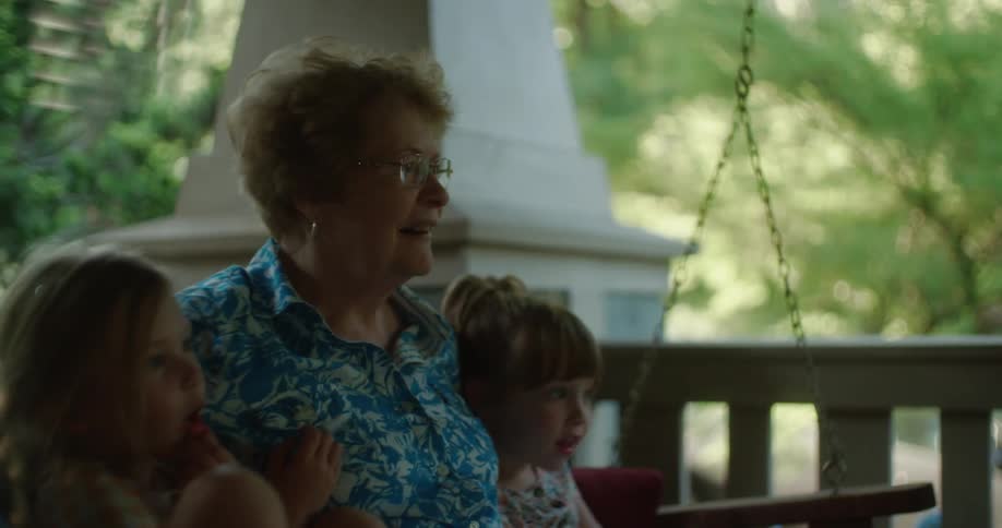 A grandmother sitting rocking with her two granddaughters