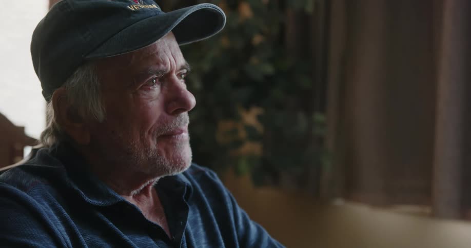 Elderly man sitting alone displays a variety of emotions while looking through photo album