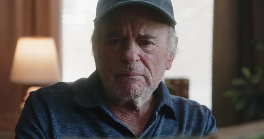 An elderly man flips through a photo album and becomes emotional