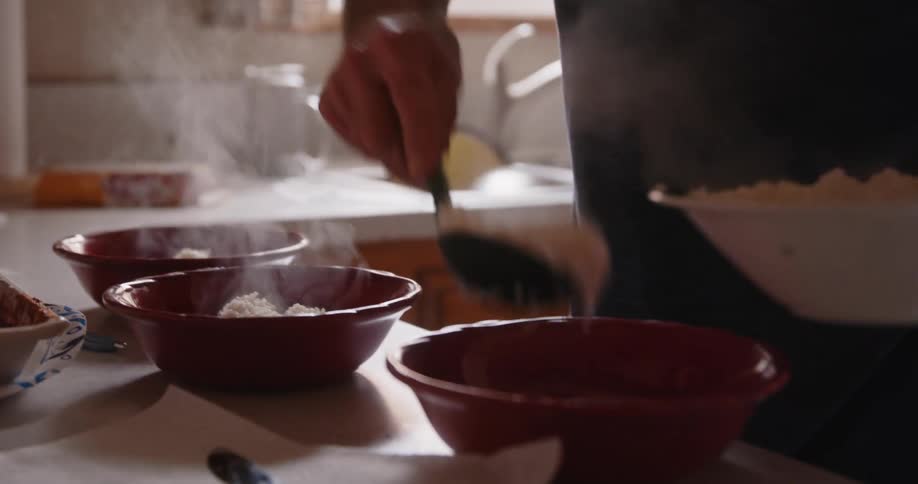 Man puts rice and food in bowls in the kitchen