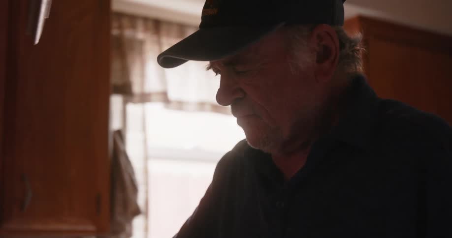 Man wearing a baseball cap cooking at home