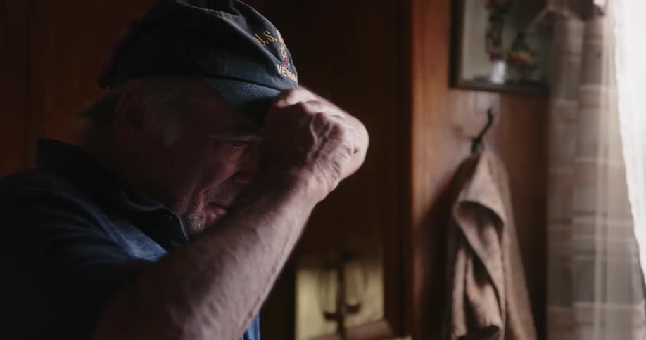A man looks sad while standing by the window