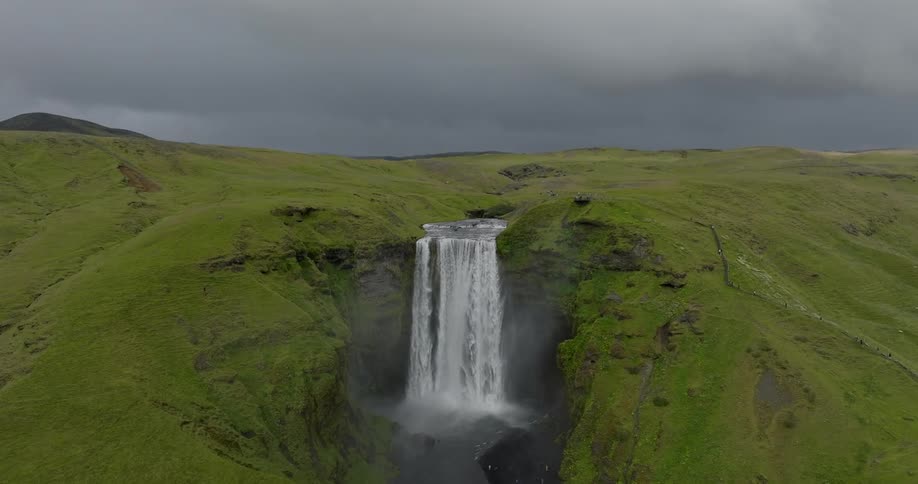 View of a waterfall amidst a mountain on a cloudy day