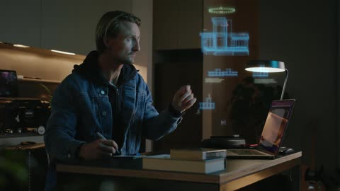 A man takes notes while looking at a hologram