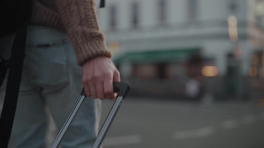 A man is dragging luggage through the city