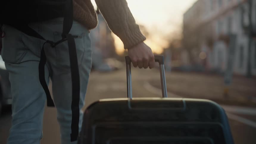 Tourist carries luggage through a town at sunset