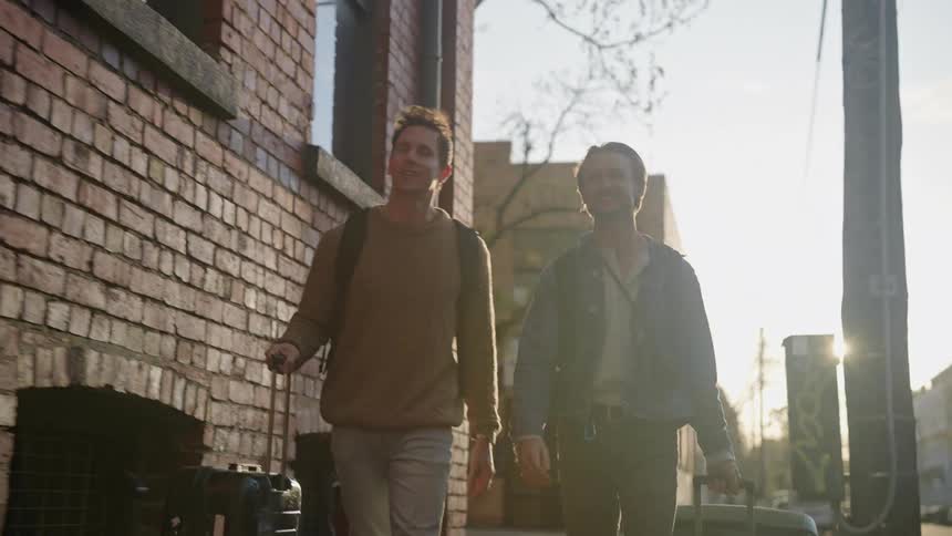 Two men holding suit cases walking on the sidewalk
