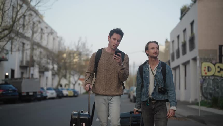 Two men walking on the road with traveling boxes at sunset
