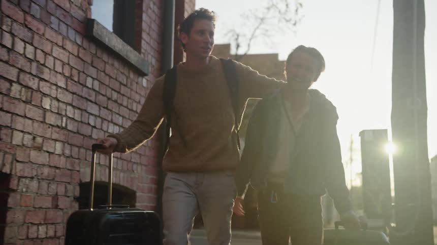 Two traveling men with boxes walking on the side walk in the evening