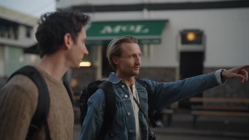 Two men walking on a city street conversing and smiling