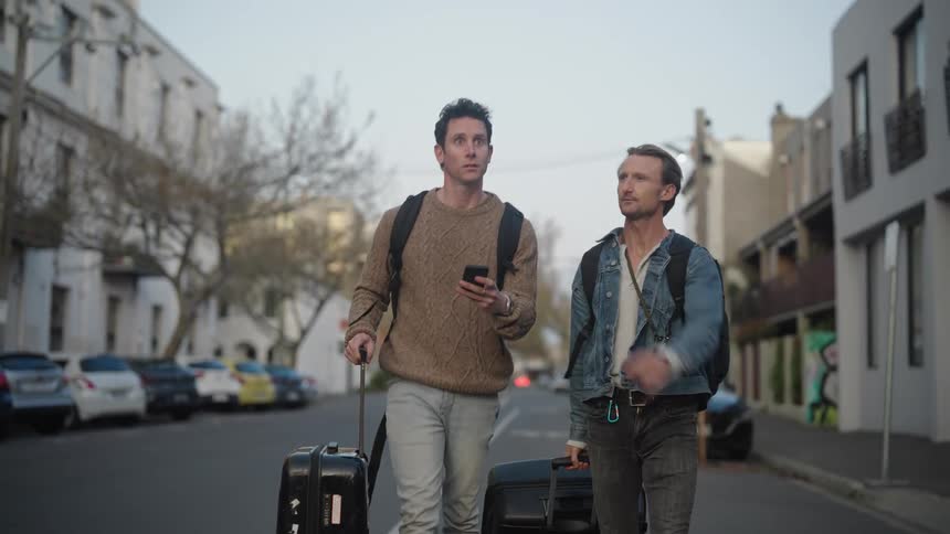 Two tourists drag their luggage down the road