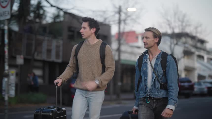 Two tourists carry luggage on the city streets