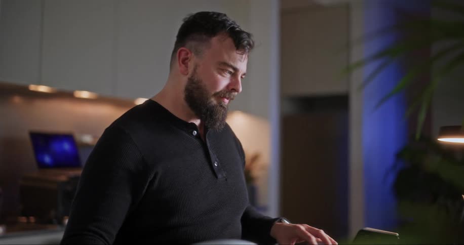 A man removes his headset and types on the laptop