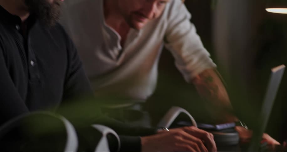 Two men talk lively while working on a laptop