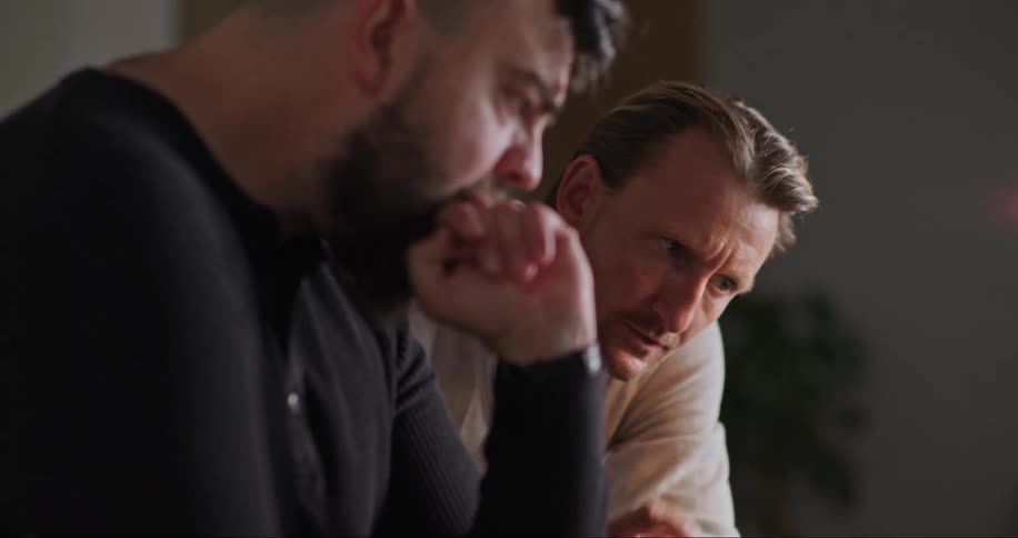 Two men attentively looking at a laptop and pointing at the screen