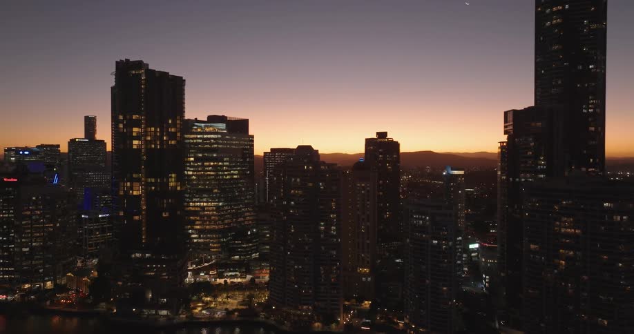 The tall buildings of a city have lights on one morning