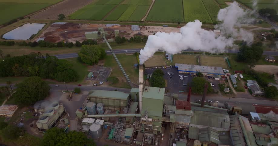 Aerial view of white smoke coming out of a factory in town
