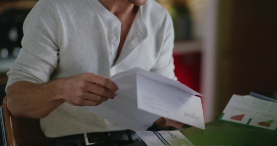 A man sitting by the desk indoor checking through some papers