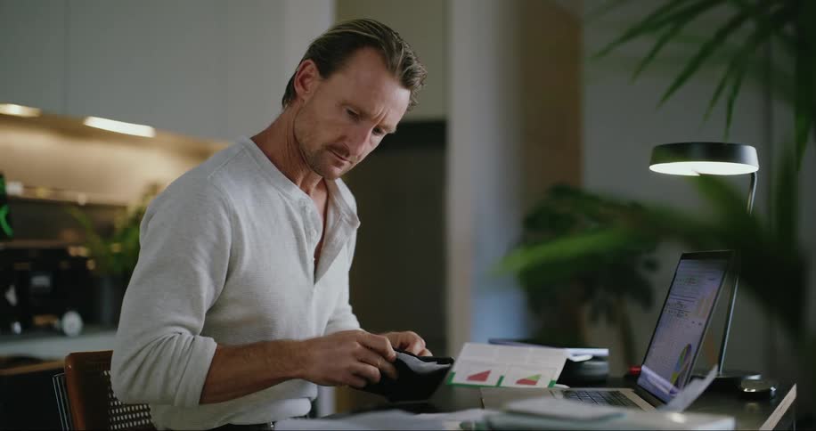 A man working indoor behind a desk with a laptop opened