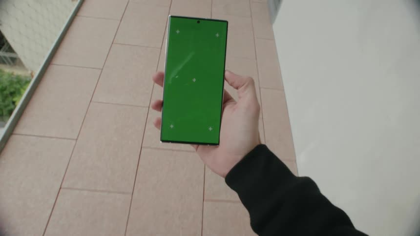 Point of view of a person holding a cellphone and walking in an outdoor corridor of a building