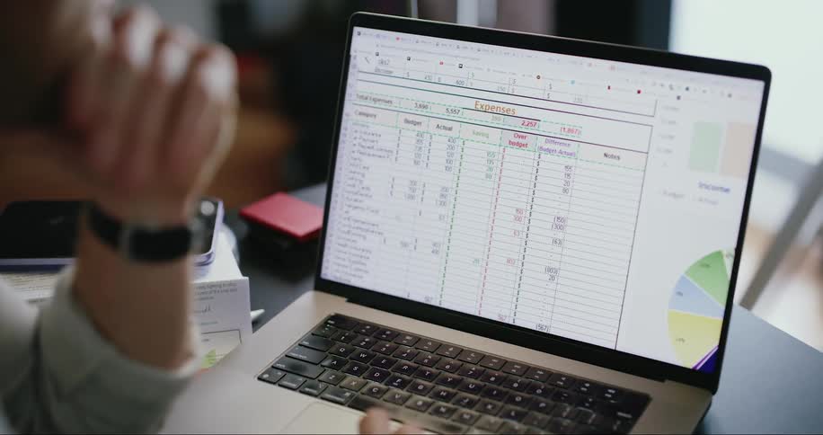 Man works on budget spreadsheet using a laptop