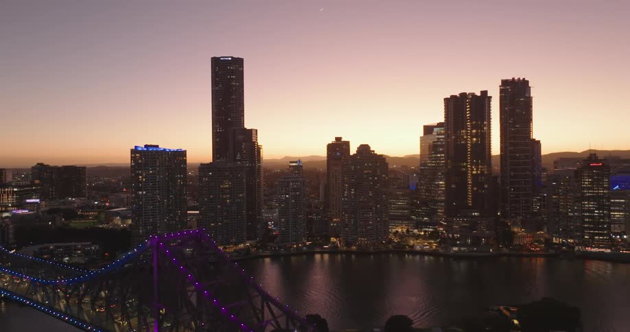 Lights on towers and skyscrapers glow on the coastal city skyline as traffic moves over the bridge
