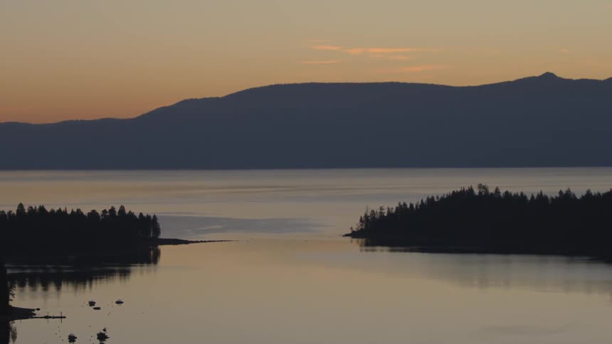 The lake water is calm as the sun sets