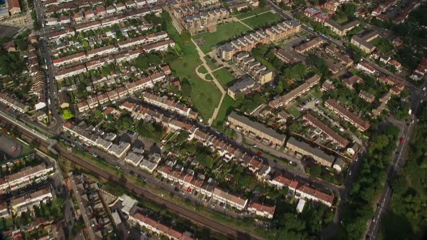 Aerial view of suburban area with streets and buildings surrounded by vegetation and trees during day time