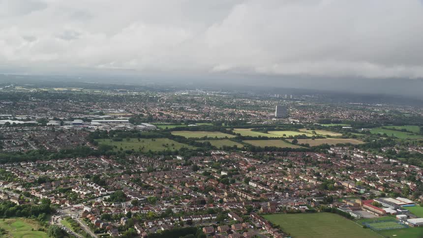 A huge rural part of a city with lots of small houses and several patches of grass