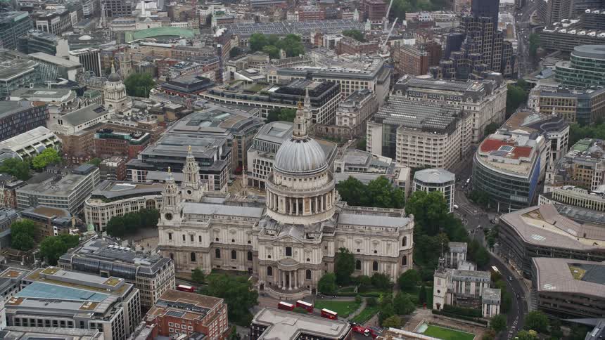Traffic moves around town and the many buildings on the streets around st pauls cathedral in london
