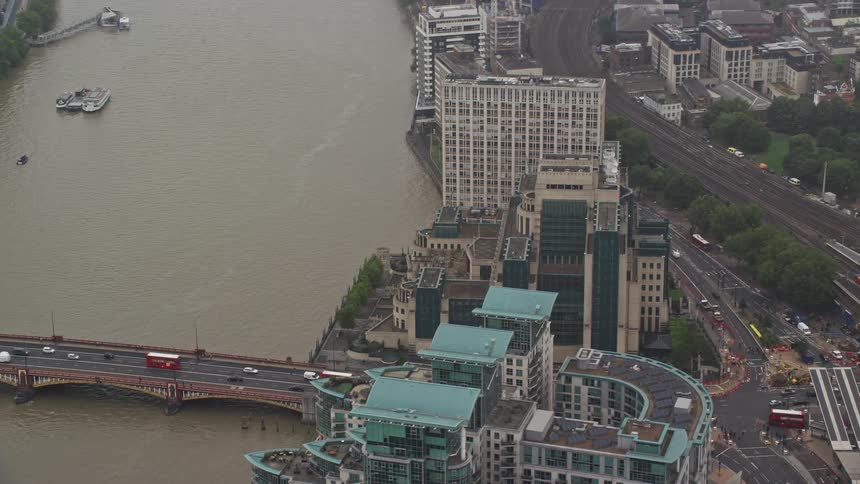 A bridge extending toward a highway flanked by towering highrise buildings that stand near the riverbank