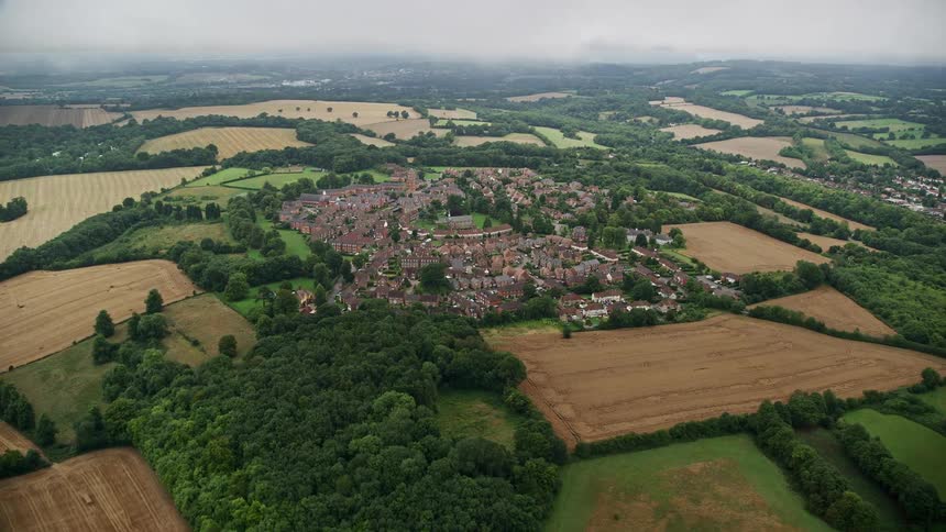 Aerial of buildings grass and trees in a suburban area at midday