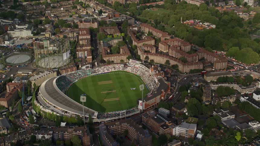Fans fill football stadium surrounded by building complexes during a game