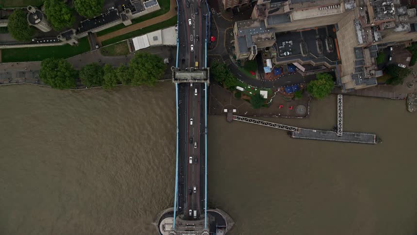 A huge bridge with many cars passing over it is above the river and there are boats passing underneath