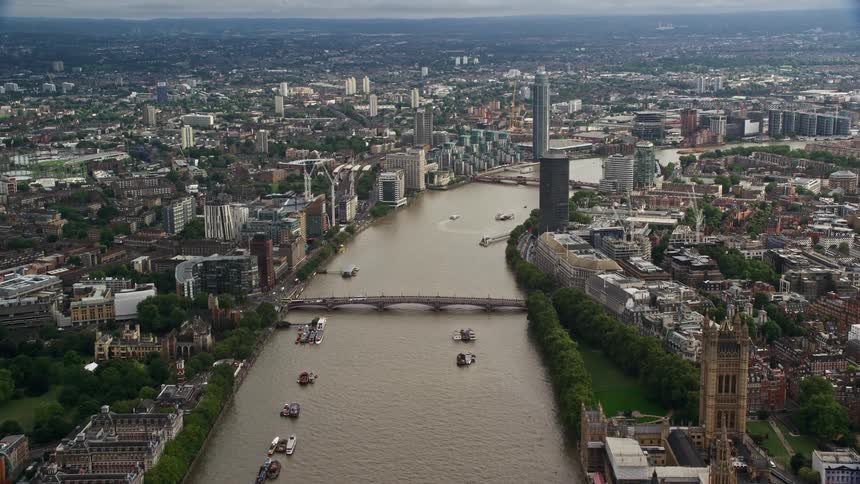 An aerial view of a city showcasing a bridge stretching across a canal with boats gliding along it within the urban landscape the city is dotted with numerous skyscrapers and towering buildings