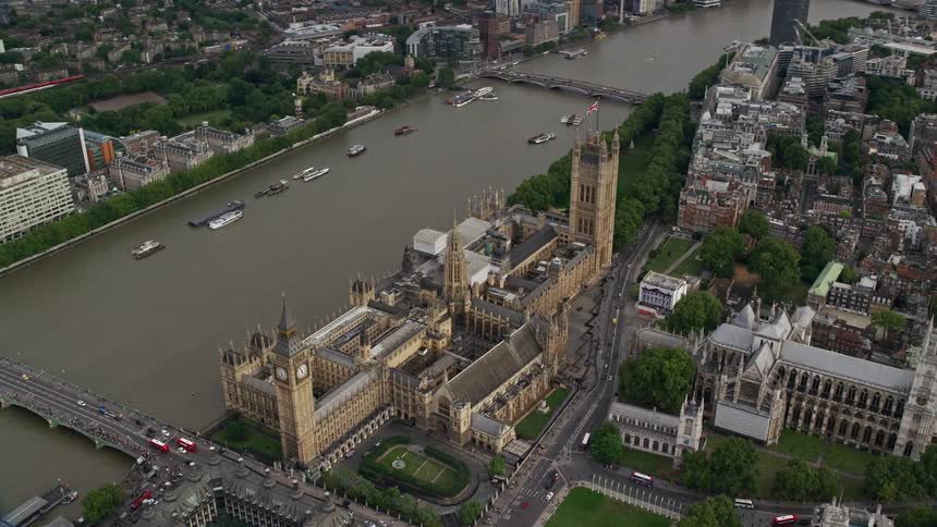 A bridge extending toward a road into the city flanked by towering highrise buildings that stand near the riverbank