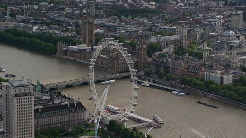 A ferris wheel is near the river in the city