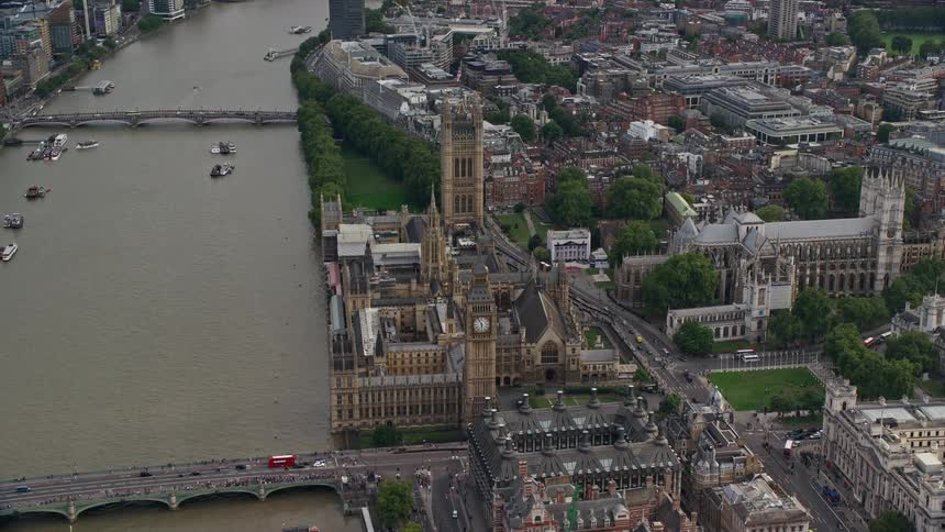 Traffic crosses bridges over a busy thames near the palace of westminster in london