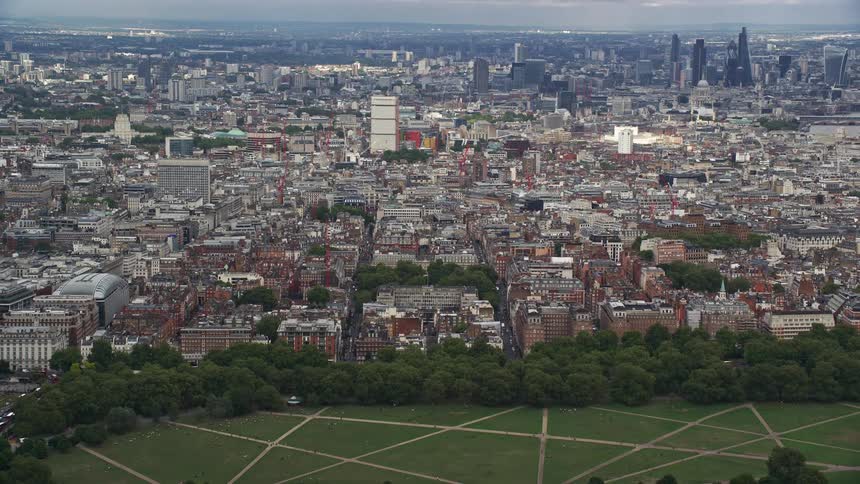 A large park with green grass and trees in a huge city that stretches to the horizon