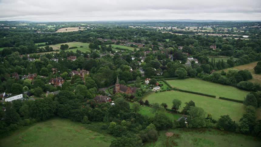 A small village with a large church in the middle of a forest and huge lawns