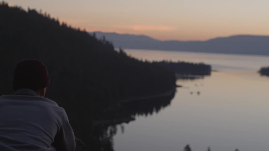 A man is taking in the view of a lake at dawn