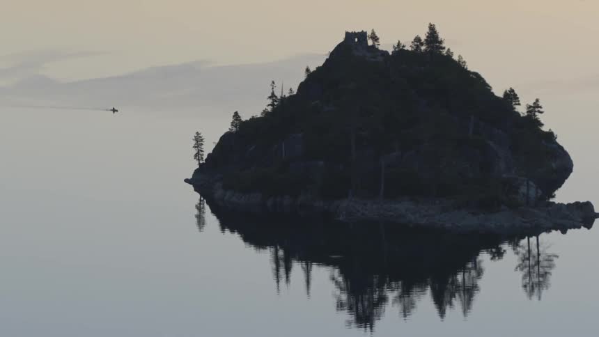 A large rock in the lake has trees on it