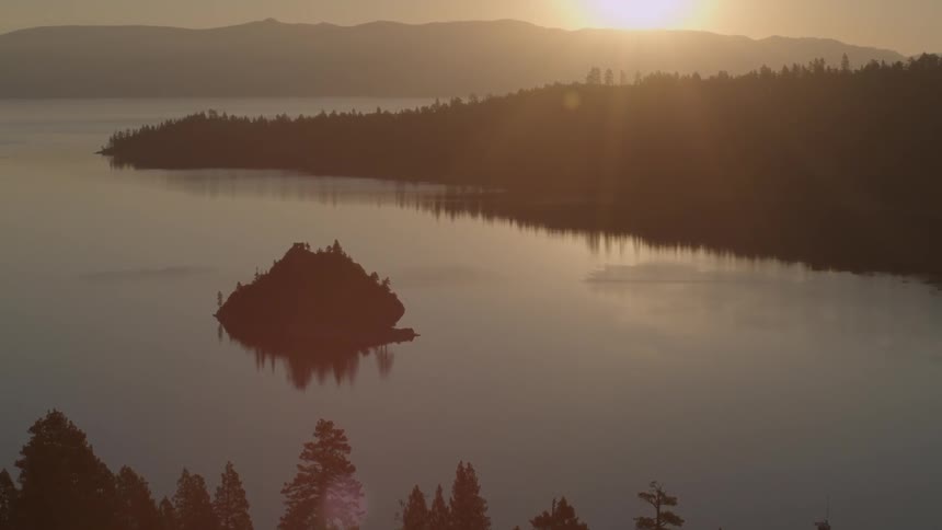 The sun is setting in the distance past this lake