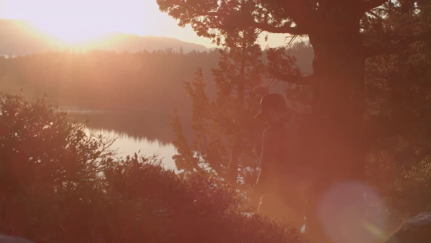 A man is hiking towards a lake at sunset