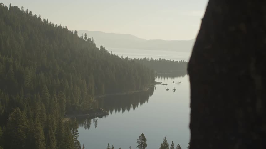 A still mountain lake reflecting trees and the overcast sky