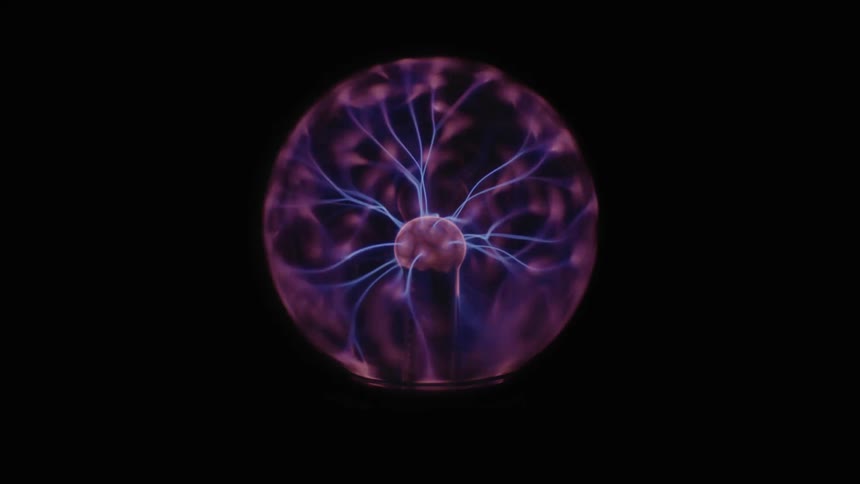 Blue sparks in a plasma ball create colorful light against black
