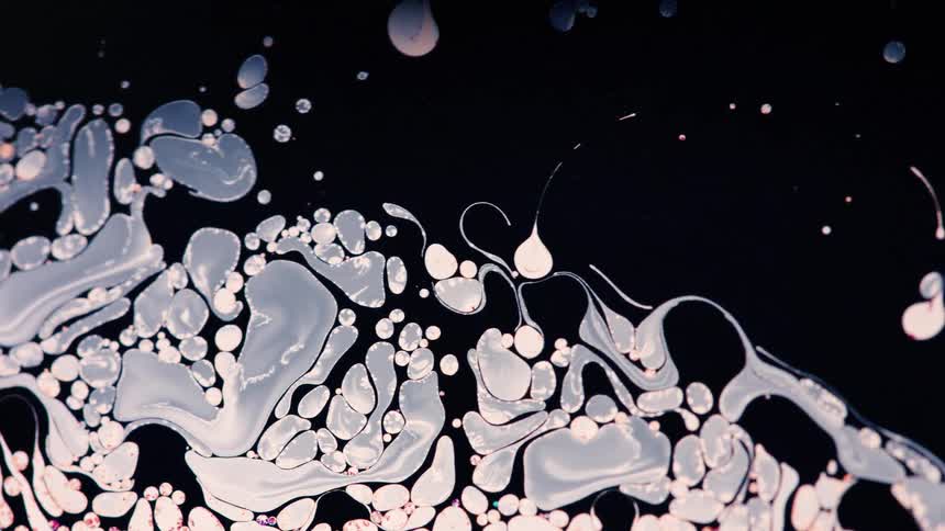 Close up of white ink flowing in black water
