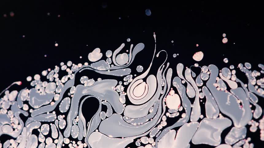 Pink and blue gray mixture floats on dark liquid