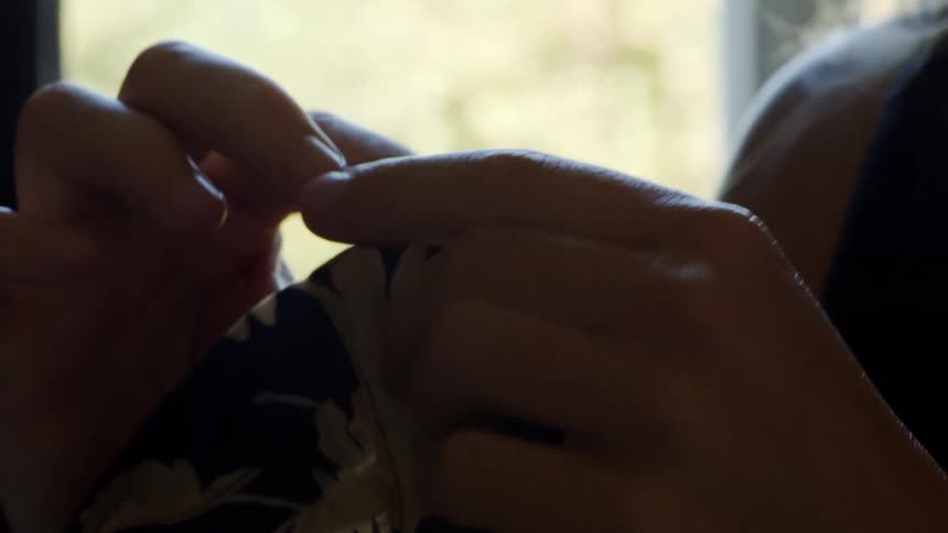 Woman handles a piece of cloth on a dimly lit room